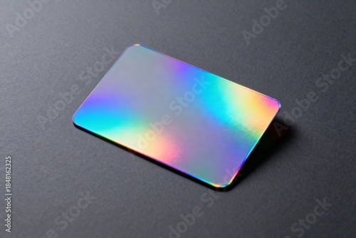A plastic or metal card (mockup) with a holographic surface reflecting rainbow colors, placed on a dark gray or black background. It conveys modernity, technology, and exclusivity.
