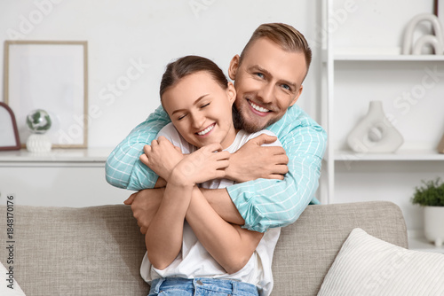 Happy young couple hugging on sofa at home