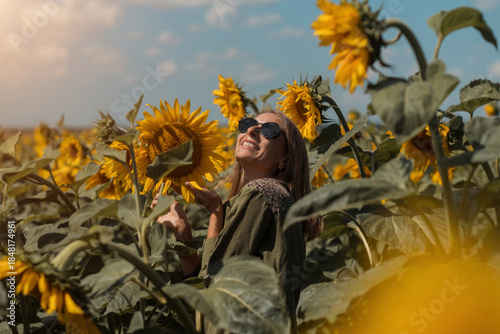 A girl in a pink skirt and a white T-shirt walks through a field of blooming yellow sunflowers. A woman dances, rejoices, smiles, enjoys life, warmth, summer, the sun. High quality FullHD footage