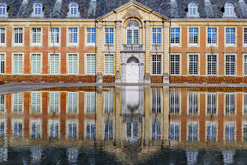 Close-up of facades of the 18th-century convent building reflected on surface of pond, multiple windows and grey gabled roof, sunny day at Averbode Abbey in Scherpenheuvel-Zichem, Belgium
