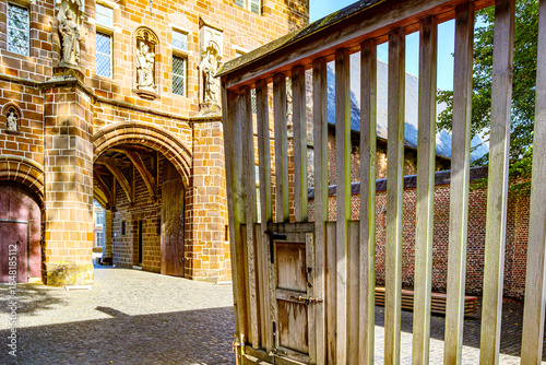 Main exterior entrance to Averbode Abbey, religious images on facade, arched passage in the 16th-century building, open gate, sunny day with blue sky in Scherpenheuvel-Zichem, Belgium