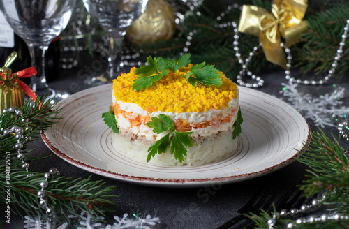 Puff salad Mimosa with canned fish, potatoes, cheese, carrots and eggs, garnished with parsley