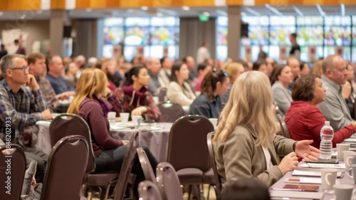 Attentive audience gathered for a keynote address in a modern hall, featuring a diverse group of people, perfect for corporate training and industry event marketing.