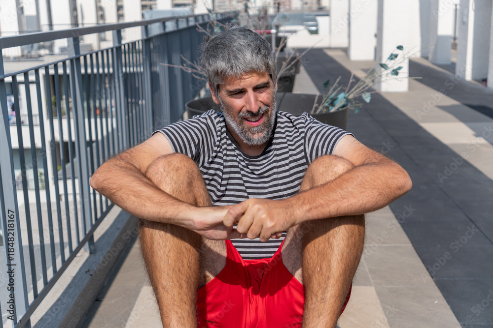 Obraz premium Mature man with grey hair and beard warming up on a urban rooftop, enjoying fitness and healthy lifestyle