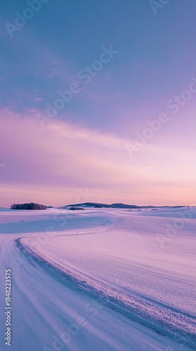 Winding snow covered rural road curves through fields under pastel twilight sky