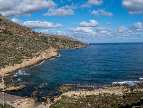 Rocky Mediterranean coastline with blue sea and scattered clouds