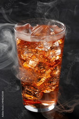 Whiskey Highball with Ice and Smoke on Dark Background. Amber Drink with Ice and Bubbles in a Glass