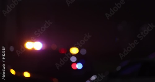 Abstracted illuminated night view of police units on a city street.