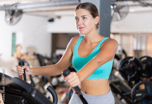 Εκτύπωση καμβά Active athlete young woman engaged in intensive high interval training on ellipsoid simulator