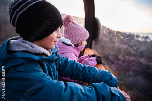 Children enjoying cable car ride with winter scenic view