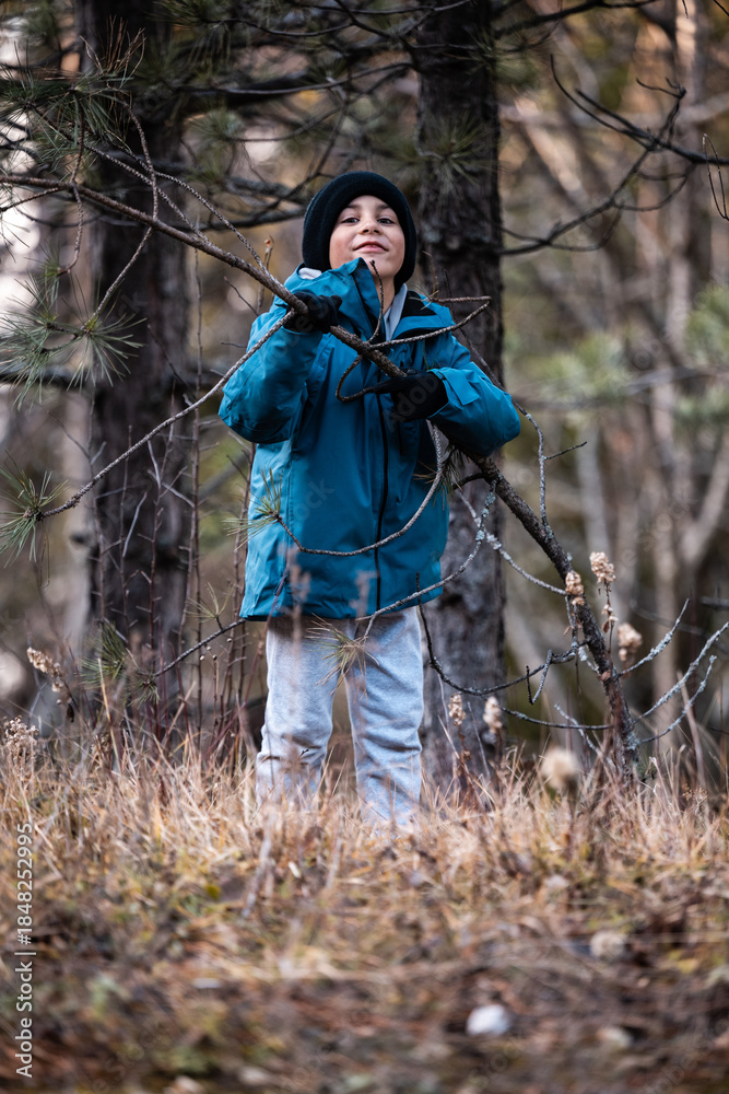 Fototapeta premium Young boy exploring winter forest nature smiling