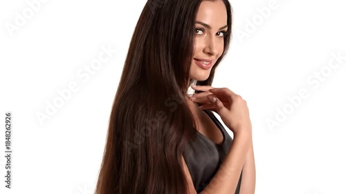 A woman with long brown hair poses, smiling gently, hand near her face. She wears a black top