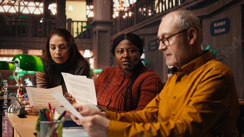 Obraz na płótnie Cast members practicing script reading for a classic drama play in a library, showing dedication to acting and passion for character development