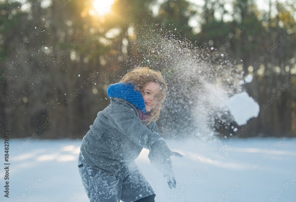 Fototapeta premium Amazed kid enjoying winter play with snowball. Happy child throwing snow outdoors. Winter outdoor playtime kid. Excited child snowball battle. Kid playing snow games. Amazed child throwing snowball.