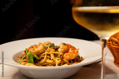 Shrimp pasta and glass of white wine close up.