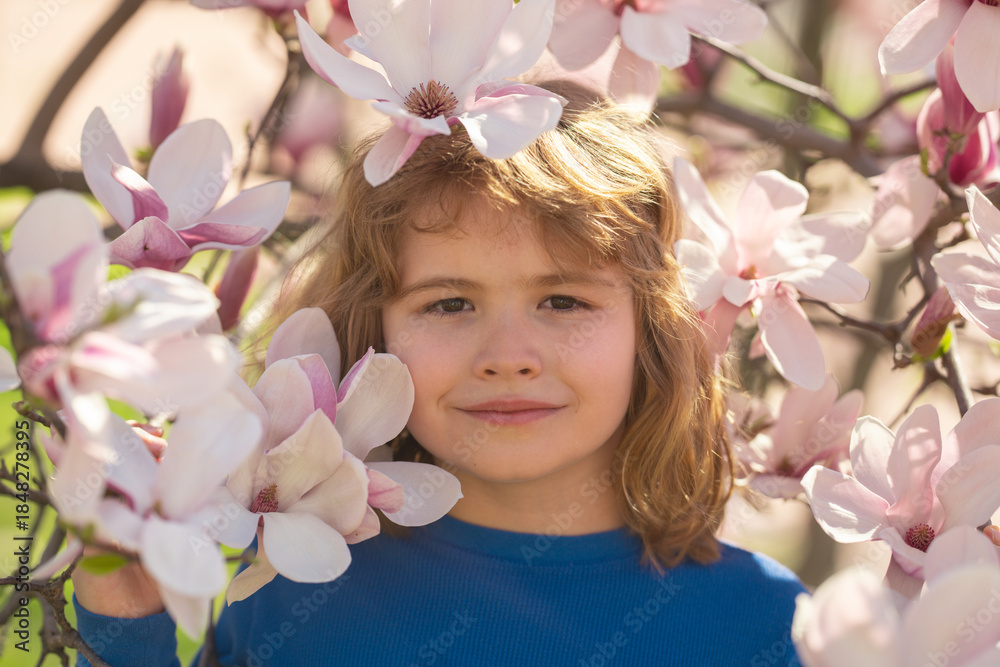 Fototapeta premium Spring fun for kids. Child play outdoors in a beautiful spring garden. Kid face in flowers. Adorable little kid in blooming cherry garden on beautiful spring day. Happy child during spring blossom.