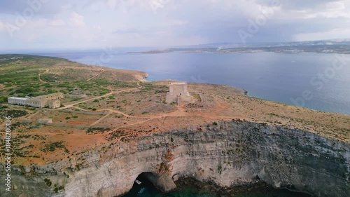 Aerial 4K 90-degree orbit shot with zoom towards St Mary's Tower on Comino island, Malta