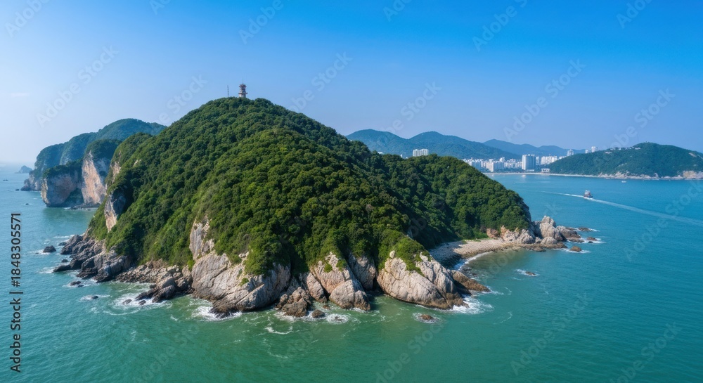 Obraz premium Panoramic view of a verdant island, rocky coastline, and clear waters. A tall structure atop the island's highest point is visible
