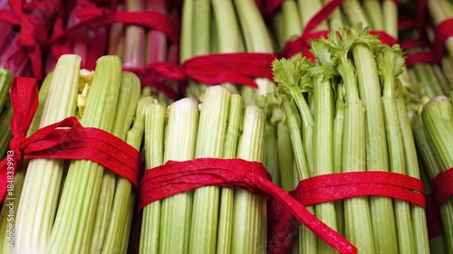 A vibrant display of fresh, crisp celery stalks, meticulously bundled with bright red ties, creates an appealing visual of wholesome produce. The varying shades of green and pale white hues of the hea