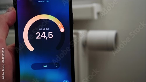 Male hand increasing thermostat temperature with data shown in mobile application.