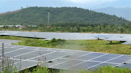 A broad solar field unfolds below a vivid sky, its reflective surfaces forming long geometric paths that lead toward gentle hills and soft clouds. Climate care.