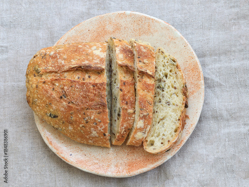 Canvas Print Top view of a sliced multigrain sourdough bread loaf on a ceramic plate