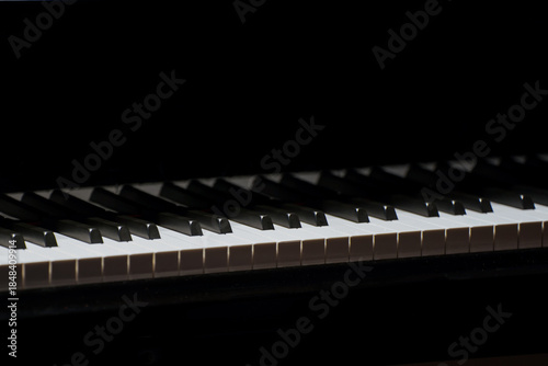 Close-up of piano keys with dramatic lighting and shadow contrast.