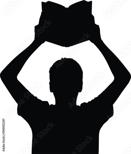 Silhouette of a person holding an open book above their head