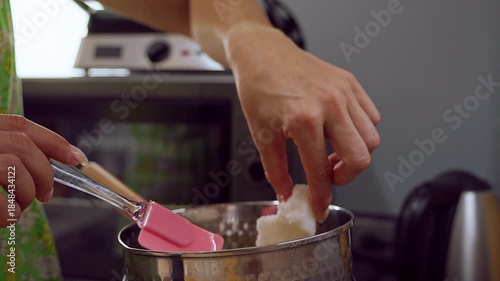 Close Up of Hand Adding Large Wax Chunk into Boiler while Holding Spatula beside Rim in Slow Motion Effect, Handmade Craft Concept