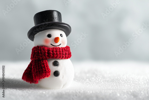 Cheerful toy snowman wearing a vibrant red scarf on glittering snow