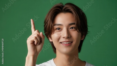 Portrait of a smiling young man with a cheerful expression raising his index finger against a