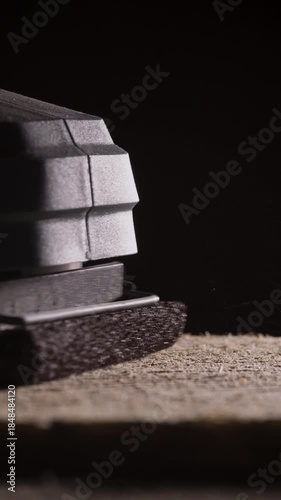 macro of industrial sanding machine what smooths a wooden board. sandpaper in carpentry process.