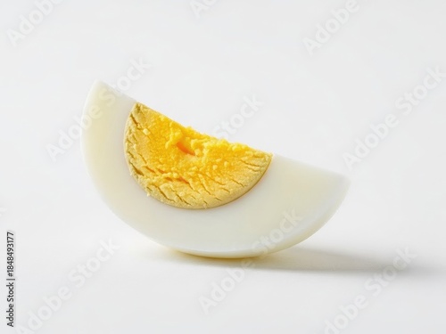 Perfectly cooked hard-boiled egg quarter with a bright yellow yolk on a clean white background