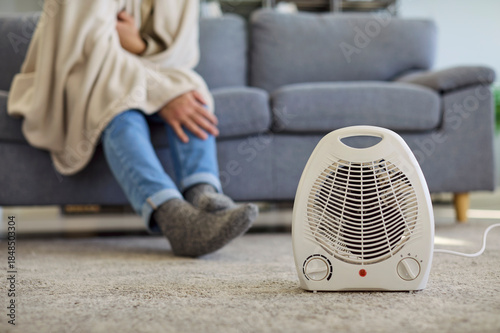 Tableau sur toile Man with blanket freezing near heater at home