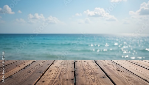 Wood tabletop foreground against blurred sparkling sea water and bright summer sky background