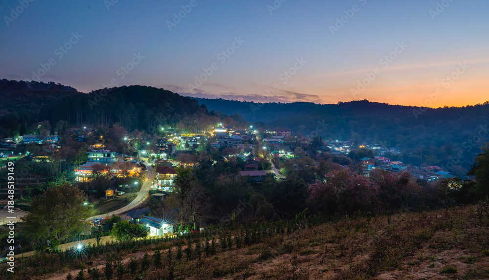 Fototapeta premium Aerial view of village with Pink Wild Himalayan Cherry tree blooming on dusk , Phitsanulok Thailand from viewpoint hill top
