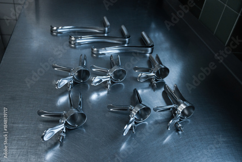 Sterilized gynecological medical instruments arranged on a stainless steel examination table in a clinical environment.