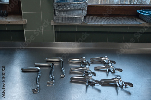 Sterilized gynecological medical instruments arranged on a stainless steel examination table in a clinical environment.