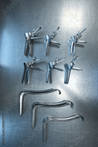 Sterilized gynecological medical instruments arranged on a stainless steel examination table in a clinical environment.