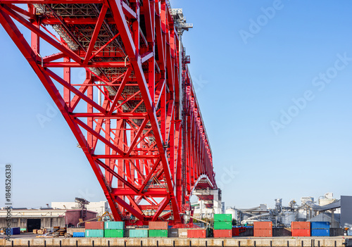 Red Steel Truss Minato Bridge Structure and Shipping Containers at Port Perspective View with Copy Space. Low angle perspective of the red Minato Bridge in Osaka, Japan.