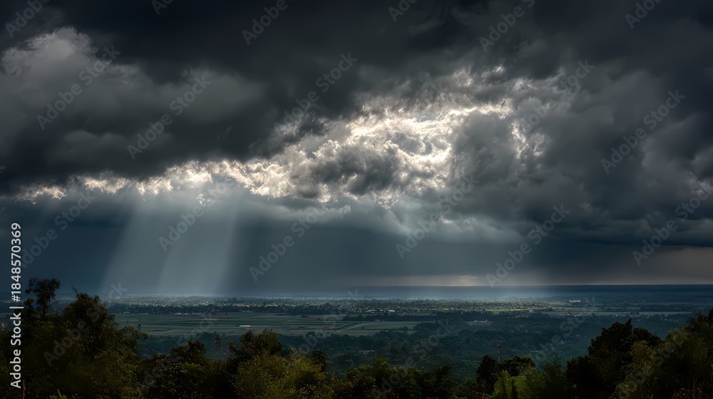 Fototapeta premium Dramatic stormy landscape with sun rays piercing through dark clouds