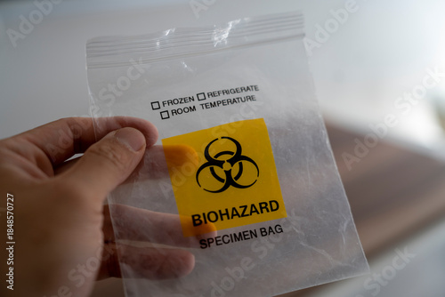 Hand holding biohazard specimen bag with warning symbol