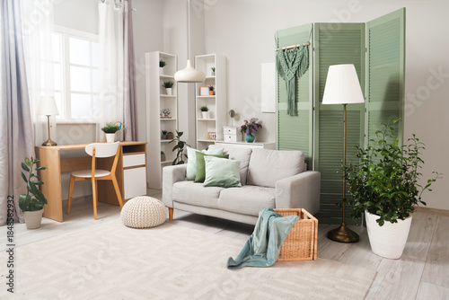 Fotografía Interior of living room with green folding screen, sofa and plants