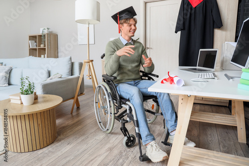 Male graduate in wheelchair video chatting at home