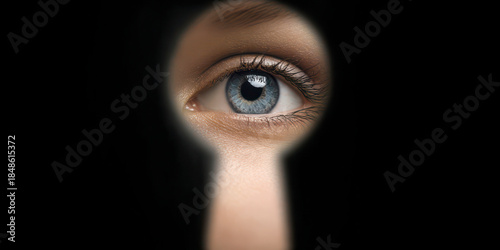 Blue eye peeking through dark keyhole
