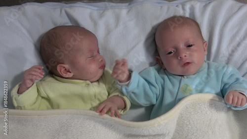 Two newborn girls lie on the bed. Two baby twins on the bed