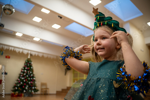Cuadro en lienzo Little girl in a Christmas tree costume in kindergarden New Year party - One person - Copy space - Low angle