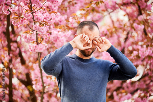 Foto Man allergic suffering from seasonal allergy at spring in blossoming garden at springtime