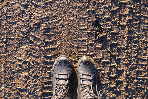 Boots on Frozen Ground. Person standing in winter boots on icy textured ground