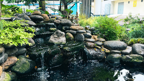 Billede på lærred Outdoor Landscape Design Featuring Artificial Stone Waterfall and Fish Pond
